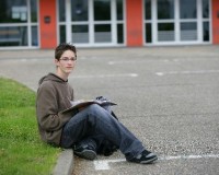 Etudiant assis sur le sol, un livre en mains