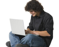 jeune homme assis par terre utilisant un ordinateur portable sur ses genoux
