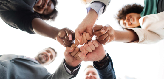Equipe d'entreprise réunie en cercle avec poings de réussite.